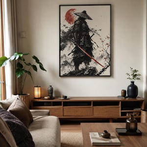 Könnte beinhalten: Ein gerahmter Wandkunstdruck, der einen Samurai in dunkler Rüstung und mit konischem Hut zeigt, vor dem Hintergrund einer großen roten Sonne, Bergen im Tusche-Stil und Kirschblütenzweigen, mit einem markanten Katana mit roter Klinge.