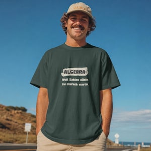 Könnte beinhalten: Ein dunkelgrünes Kurzarm-T-Shirt mit dem weißen Text "ALGEBRA: Weil Zahlen allein zu einfach waren." auf der Brust. Das T-Shirt hat einen Rundhalsausschnitt und eine lockere Passform, kombiniert mit einer hellbraunen Baseballkappe.