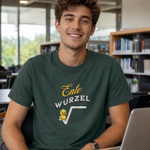 Könnte beinhalten: Ein dunkelgrünes Kurzarm-T-Shirt mit dem gelben Schriftzug Ente und dem weißen Schriftzug WURZEL über einer Grafik eines kleinen gelben Entleins, das in einem Quadratwurzelsymbol sitzt, zentriert auf der Brust des Rundhals-Kleidungsstücks.