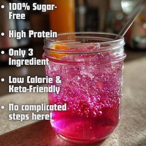 Può includere: Un barattolo di vetro trasparente pieno di una vivace bevanda rosa, ghiaccio e una fetta d'arancia. Il testo sul lato sinistro del barattolo recita: "100% senza zucchero", "Alto contenuto proteico", "Solo 3 ingredienti", "A basso contenuto calorico e Keto-Friendly" e "Nessun passaggio complicato qui!"
