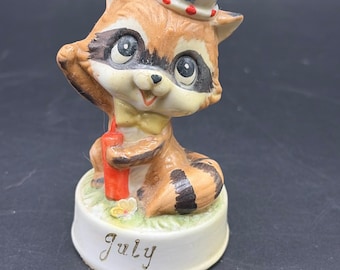 Figura vintage de mapache patriótico con forma de petardo, nacida en julio.