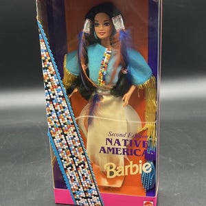 May include: A Special Edition Native American Barbie doll from the Dolls of the World Collection. The doll is in a clear plastic box with a pink and blue design. The doll wears a turquoise top, a white skirt, and has long black hair with blue and purple feathers.