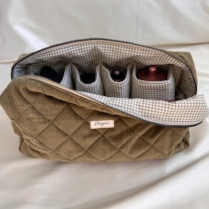 May include: Open olive green quilted corduroy cosmetic bag with a gingham lining and interior compartments. The bag has a zipper closure and a small label that reads "Elvya".