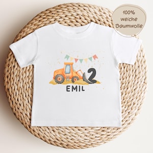 K&ouml;nnte beinhalten: Ein wei&szlig;es Kurzarm-T-Shirt mit einer Grafik eines orangefarbenen Baggers, der schwarzen Zahl 2 und dem Namen EMIL in dunkelgrauen Buchstaben. &Uuml;ber dem Bagger befinden sich bunte dreieckige Wimpel und goldene Sprenkel.