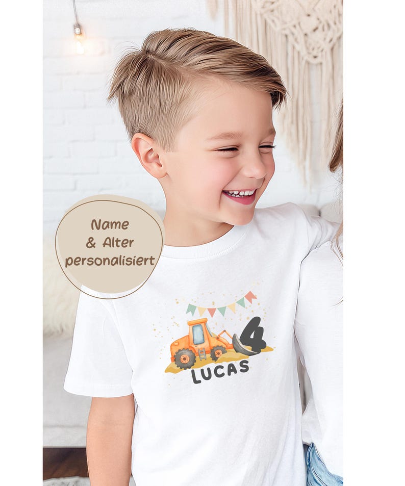 K&ouml;nnte beinhalten: Ein wei&szlig;es T-Shirt mit kurzen &Auml;rmeln, das mit einer Grafik eines orangefarbenen Baggers, der schwarzen Zahl 4 und dem Namen LUCAS in schwarzer Schrift bedruckt ist. &Uuml;ber dem Bagger befindet sich eine bunte Wimpelkette.