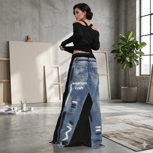May include: A woman in a black off-the-shoulder top and a long skirt. The skirt combines black fabric and denim jeans, featuring white paint details and the text "wearium craft". The background is a studio with art supplies.