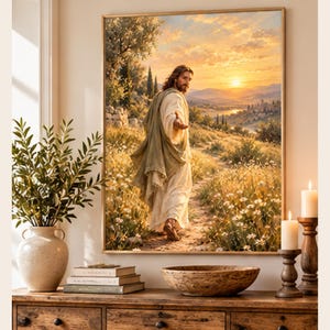 May include: A framed wall art print depicting a figure with long hair wearing a light-colored robe and a green shawl, walking along a dirt path through a field of white flowers toward a sunset landscape with rolling hills and trees.