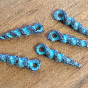 May include: Five turquoise blue metal spiral charms with a hole at the top for attaching to jewelry or other crafts.