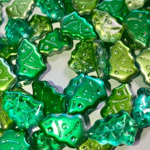 May include: A collection of green and light green glass Christmas tree ornaments. The ornaments are shiny and have a metallic finish.