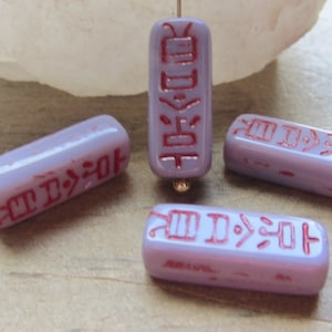 May include: Four purple glass beads with red hieroglyphic-like markings. The beads are rectangular in shape and have a glossy finish.
