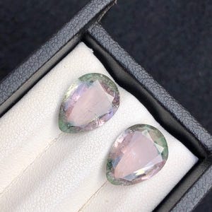 Puede incluir: Una taza de cerámica blanca con un asa negra y el texto "But First, Coffee" en negrita negra. La taza se encuentra sobre un fondo borroso, sugiriendo un ambiente acogedor.