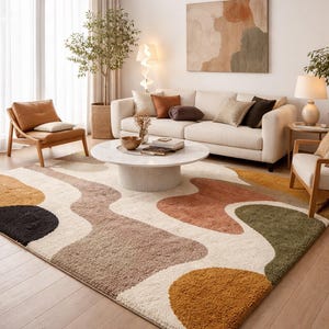 May include: A living room scene featuring a cream-colored sofa, a round coffee table, and a patterned rug. The rug has an abstract design with shapes in black, brown, orange, and green. A wooden chair and a painting are also visible.