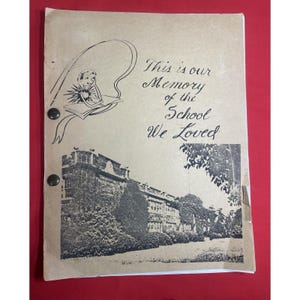 May include: A vintage school yearbook with a brown cover. The cover features a black and white illustration of a school building and a student reading a book. The text reads "This is our Memory of the School We Loved."