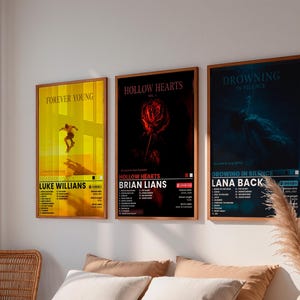Könnte beinhalten: Drei rechteckige Wandposter in Holzrahmen. Das linke Poster ist gelb mit einem Skateboarder und dem Text "FOREVER YOUNG" und "LUKE WILLIAMS". Das mittlere ist schwarz mit einer roten Rose und "HOLLOW HEARTS" und "BRIAN LIANS". Das rechte ist blau mit "DROWNING IN SILENCE" und "LANA BACK".