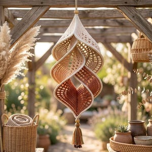 May include: A hanging crochet spiral ornament featuring a gradient colour scheme that transitions from cream at the top to a deep terracotta at the bottom. The piece is constructed with an openwork stitch pattern and finished with a wooden bead and tassel.