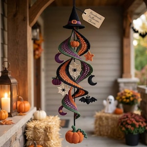 May include: A crocheted Halloween hanging decoration featuring a black witch hat at the top, a spiral structure in orange, purple, and black, and dangling motifs including pumpkins, stars, moons, spiders, webs, and a bat, with a tag reading Handmade Halloween Charm.