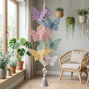 Può includere: Una giostrina verticale da appendere con una serie di farfalle all'uncinetto in tonalità pastello viola, blu, rosa, verde menta e giallo, fissate a un cordino centrale con una perla di cristallo trasparente e una nappa multicolore in fondo.