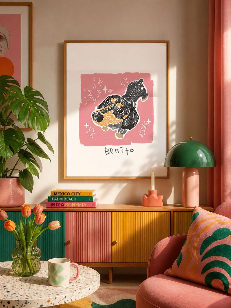 May include: A framed wall art print featuring a black and tan dachshund illustration on a pink background with white star accents and the name Benito written in black ink below the dog. The artwork is displayed in a simple wooden frame.