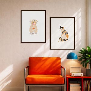 May include: Two framed wall art prints featuring illustrations of pets. The left print shows a tan dog with the text MY BOY, BOR! underneath. The right print displays a calico cat with the text KITTY underneath. Both prints have dark brown frames.