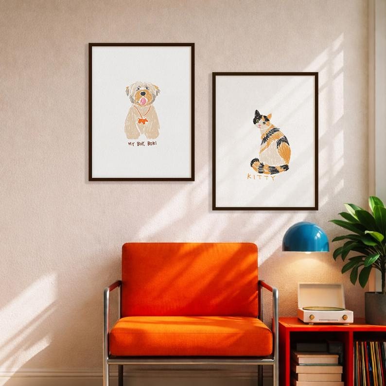 May include: Two framed wall art prints featuring illustrations of pets. The left print shows a tan dog with the text MY BOY, BOR! underneath. The right print displays a calico cat with the text KITTY underneath. Both prints have dark brown frames.