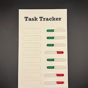 Op de afbeelding: Een wit Task Tracker-bord met rechthoekige sleuven en verschuifbare voortgangsindicatoren. De tekst "Task Tracker" staat bovenaan afgedrukt. Voortgangsindicatoren zijn groen, wit en rood.