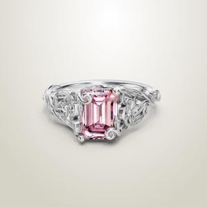 May include: A white ceramic mug with a black handle and the text "But First, Coffee" in a black, handwritten-style font. The mug is on a white surface.