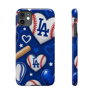 Puede incluir: Una funda de teléfono azul con un patrón repetitivo de corazones blancos con forma de pelotas de béisbol con el logo LA azul, un bate de béisbol de madera, corazones azules sólidos y estrellas blancas. El diseño cubre la parte trasera y lateral.