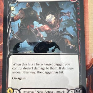 May include: A trading card titled "Pain in the Backside" features an illustration of two figures in combat. The card text describes the card's action and effects. The card is labeled as an Assassin/Ninja Action-Attack.