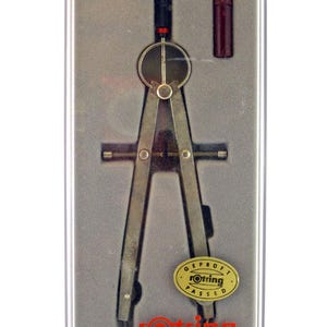 May include: A silver-toned compass set in a clear plastic case. The compass has a black handle and a red adjustment wheel. A small, maroon-colored tube is included. The case has a gray interior and the Rotring logo is visible.
