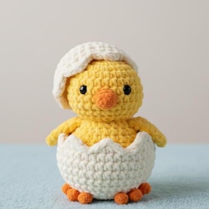 Peut inclure: Un poussin au crochet sortant d'une coquille d'œuf blanche. Le poussin est jaune avec un bec orange et de petits yeux noirs. La coquille d'œuf est blanche et texturée, et le poussin porte un chapeau blanc. Les pieds du poussin sont orange.