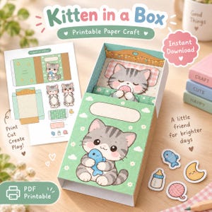 Peut inclure: Un kit de loisirs créatifs en papier intitulé Kitten in a Box représentant un chaton tigré gris. L'ensemble comprend une feuille de modèle à plat et une boîte assemblée en trois dimensions avec un chaton endormi à l'intérieur, ainsi que des accessoires découpés comme un poisson, un biberon, une lune et une pelote de laine.