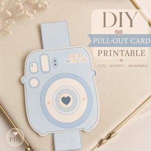 May include: A light blue DIY pull-out card printable with a camera design. The card features the text "Guess Who I See" and a heart-shaped design in the center. The card is on a neutral background with the words "Cute, Aesthetic, Meaningful".