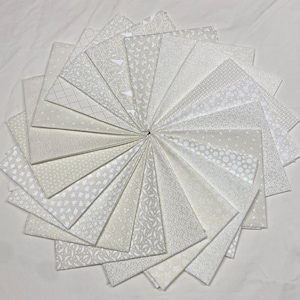 May include: A collection of white fabric squares arranged in a circular pattern. Each square features a unique, subtle pattern, including dots, geometric shapes, and floral designs. The fabrics are a variety of off-white shades.