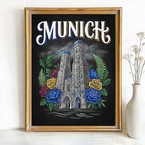 May include: Framed art print featuring the word "MUNICH" in white script above a detailed illustration of a cathedral with blue domes, surrounded by colorful flowers. The artwork is set against a black background within a gold frame.