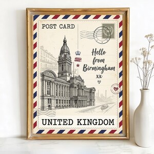 May include: Framed postcard print featuring a detailed black and white illustration of a building with a clock tower. The postcard reads "Hello from Birmingham" and "United Kingdom" with red, white, and blue accents. A white vase with flowers is to the right.