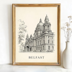 May include: Framed black and white sketch of a building with multiple domes and columns, labeled "Belfast." The artwork is in a gold frame, and a white vase with dried flowers is to the right.