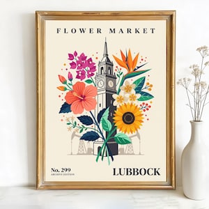 May include: A framed art print with a gold frame featuring a floral design and a clock tower. The print includes the text "FLOWER MARKET" and "LUBBOCK". The artwork showcases a vibrant arrangement of flowers, including hibiscus, sunflowers, and bird of paradise.