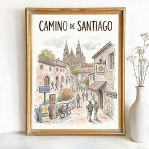 May include: Watercolor print in a gold frame depicting the Camino de Santiago. The artwork shows a street scene with buildings, people, and a cathedral in the background. Text at the top reads "CAMINO DE SANTIAGO".