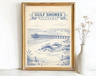 May include: A framed print featuring a blue and white illustration of Gulf Shores, Alabama. The artwork depicts a pier extending into the ocean, with sand dunes and beach vegetation in the foreground. The words "Gulf Shores Alabama" are displayed in a banner at the top.