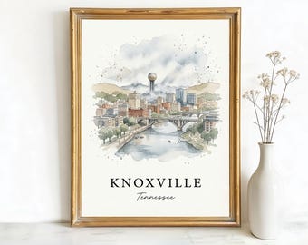 May include: A framed watercolour print of Knoxville, Tennessee. The artwork shows a cityscape with a river, bridges, and buildings. The text "KNOXVILLE Tennessee" is at the bottom. A white vase with dried flowers is to the right of the frame.