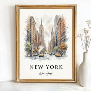 May include: Watercolor print of a New York City street scene, framed in gold. The artwork depicts iconic skyscrapers, cars, and trees. The text "NEW YORK" and "New York" are printed at the bottom of the image.