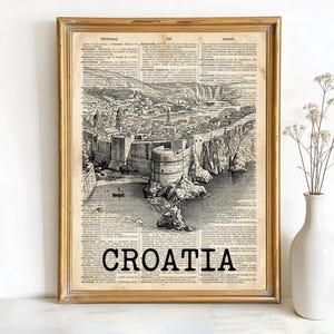 May include: Framed vintage print of a Croatian coastal city, featuring a detailed black and white illustration set against a dictionary page background. The word "CROATIA" is printed in bold black letters at the bottom.
