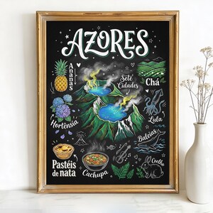 May include: A framed chalkboard-style print with the word "AZORES" in white script. The print features colorful illustrations of local flora, fauna, and cuisine, including a pineapple, hydrangeas, and a whale. The frame is gold.