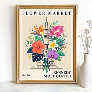 May include: A framed art print with a retro design. The image depicts a rocket surrounded by vibrant flowers, with the words "FLOWER MARKET" and "KENNEDY SPACE CENTER." The print is in a gold frame, suitable for wall decor.