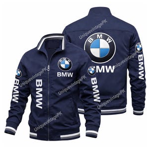 Puede incluir: Chaqueta azul marino con cremallera y el logotipo de BMW en la parte delantera y trasera. La chaqueta tiene detalles blancos en el cuello, los puños y el dobladillo, con el logotipo y el texto de BMW impresos en las mangas. El texto "BMW" también está impreso en la parte delantera.