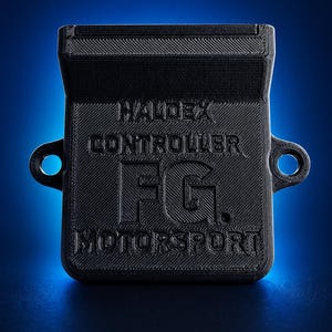 Puede incluir: Un componente negro Haldex Controller FG Motorsport, con el nombre de la marca y los detalles del producto en relieve. El dispositivo rectangular tiene una superficie texturizada y dos orificios de montaje circulares. El fondo es un degradado azul.