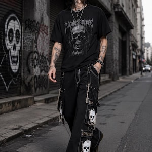 May include: Black t-shirt with a skull graphic and the word "BLOODSBIRTH". The outfit includes black trousers with skull patches and chains. The person is walking on a city street.