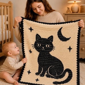 May include: A rectangular crochet blanket featuring a cream-colored background with a large black cat graphic in the center. The design includes a black crescent moon and several small four-pointed stars, finished with a black scalloped border.