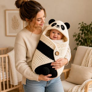 May include: A crochet baby swaddle blanket designed to look like a panda, featuring a cream-colored hood with black ears and panda facial features, a black and cream body, and a single brown wooden button closure on the front side.