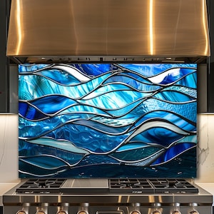 Könnte beinhalten: Eine rechteckige Küchenrückwand mit einem abstrakten Design aus fließenden, geschichteten Wellen in tiefem Marineblau, Königsblau und hellem Cyan, die durch erhabene, metallisch silberne Linien getrennt sind und einen strukturierten Effekt erzeugen.